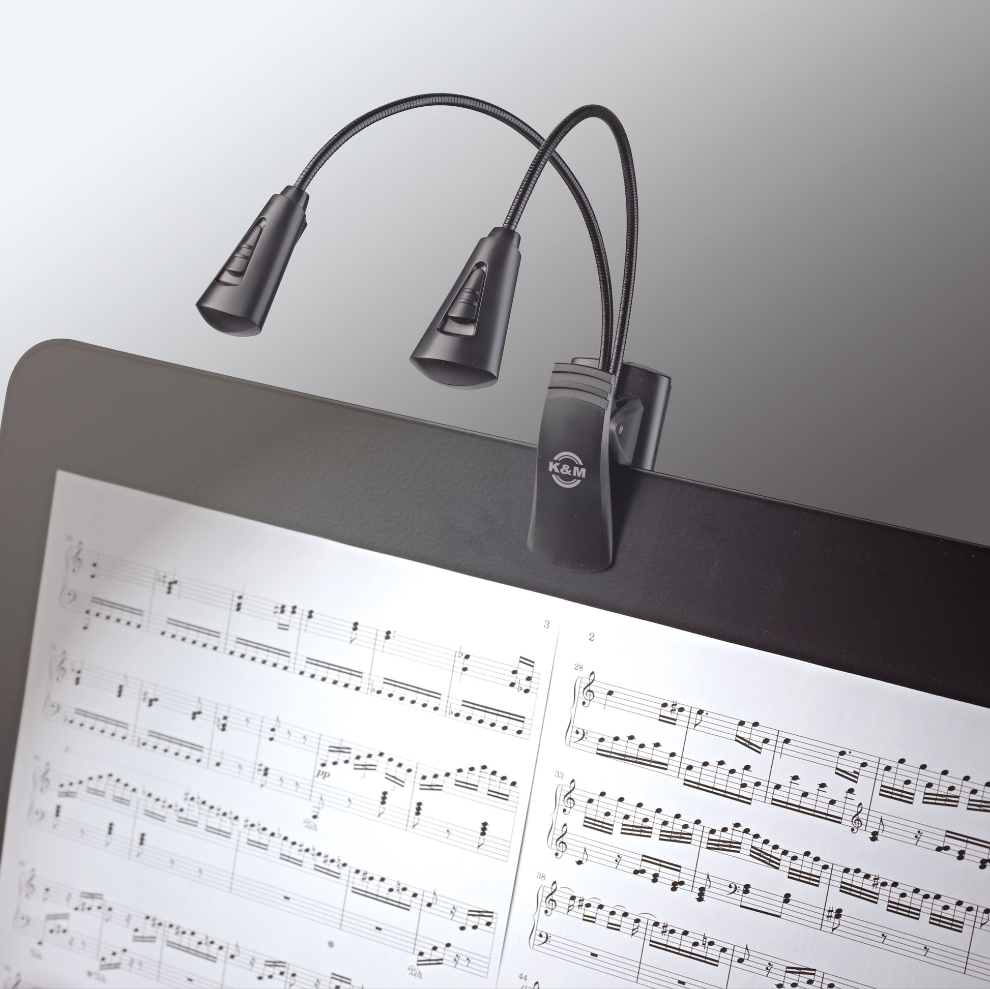K&M 12244 music stand light with adjustable arm and bright LED, illuminating sheet music for clear visibility.