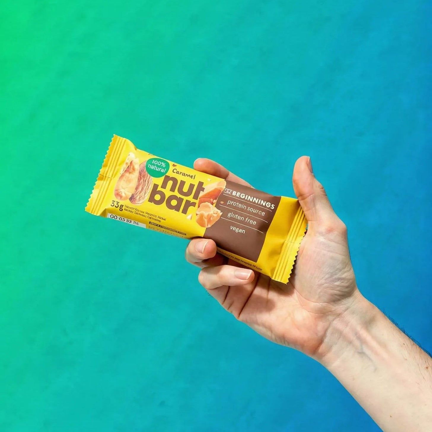 Hand holding a Nut Bar against a gradient blue and green background