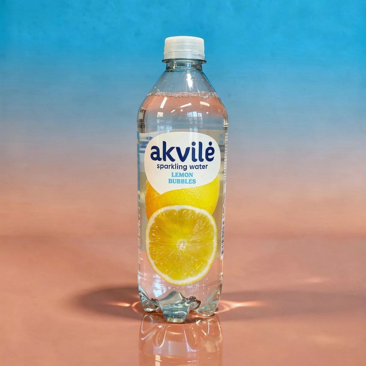 Akvile sparkling water bottle with lemon flavor on a reflective surface and blue background